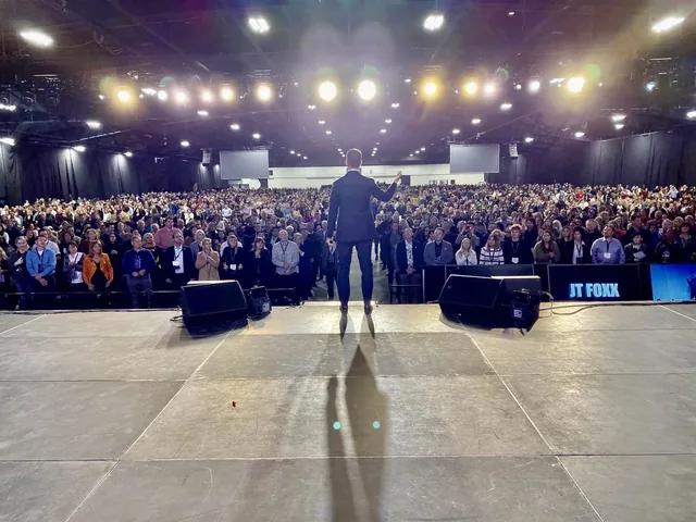 JT Foxx on stage facing a large conference audience